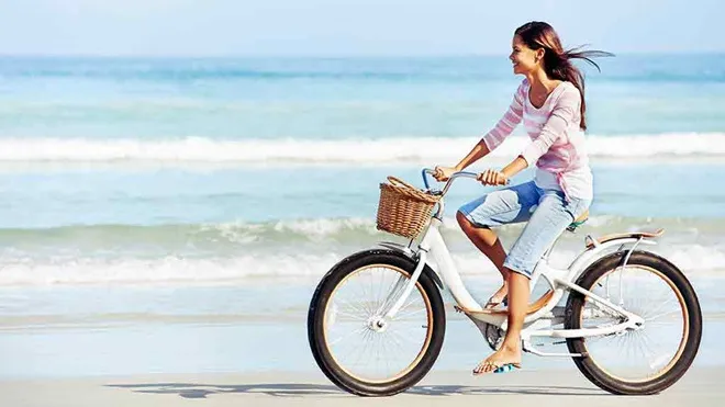 Iia young girl rides on the beach in langebaan with a bicycle enjoying on the beach rides in langebaan